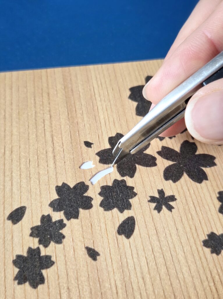 制作中の手元の写真。カッターと木の繊細な質感が感じられる。木を切り抜いたあとの「窓」が白く映る。